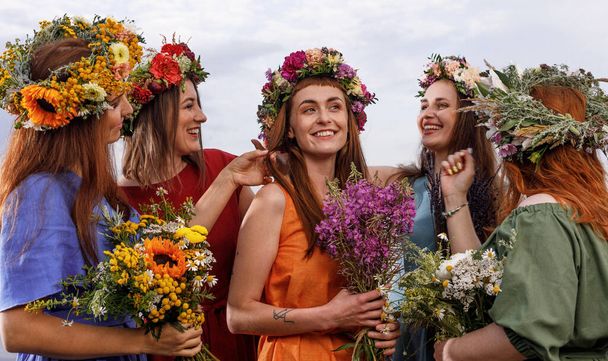 Lovely girls in flower wreaths in nature. Ancient pagan origin celebration concept. Summer solstice day. Mid summer. - Foto, Imagen