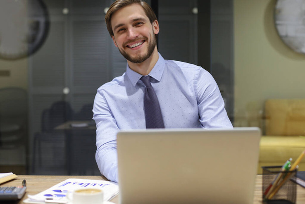 Šťastný moderní obchodník pracující pomocí notebooku, zatímco sedí v kanceláři - Fotografie, Obrázek