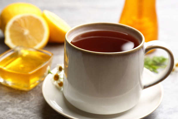 Tea with honey and lemon on grey table, closeup - Фото, изображение