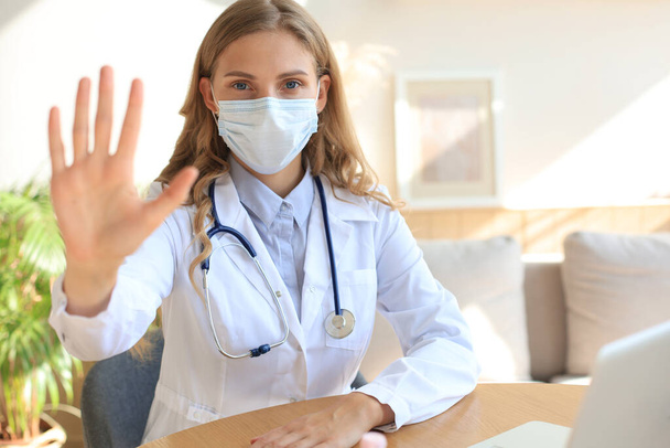 Female doctor in face mask showing stop sign with her hand. - Foto, Imagem