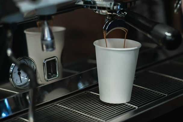 Der Prozess, Kaffee auf einer Kaffeemaschine zuzubereiten. Der Kaffee wird aus dem Halter in einen Pappbecher geschüttet. - Foto, Bild