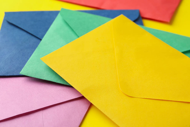 Kleurrijke papieren enveloppen op gele achtergrond, close-up - Foto, afbeelding