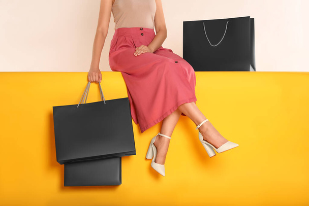 Woman with shopping bags sitting on yellow background, closeup. Black Friday - Foto, afbeelding