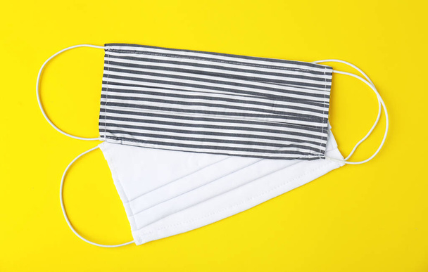Homemade protective face masks on yellow background, flat lay - Fotografie, Obrázek