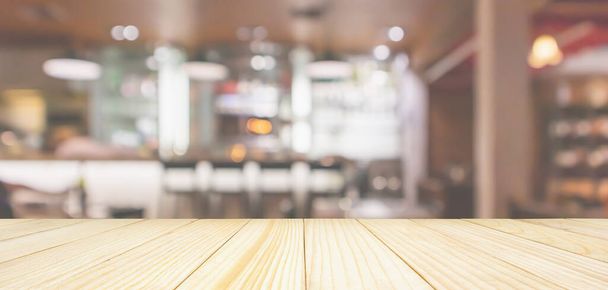 Holz Tischplatte mit Cafe Restaurant Interieur mit Theke verschwimmen abstrakten Hintergrund mit Bokeh-Licht - Foto, Bild