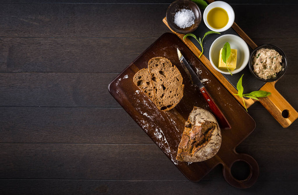 Atún con rebanada de pan fresco, mantequilla de salvia, aceite de oliva y sal sobre una mesa rústica de madera.  - Foto, Imagen