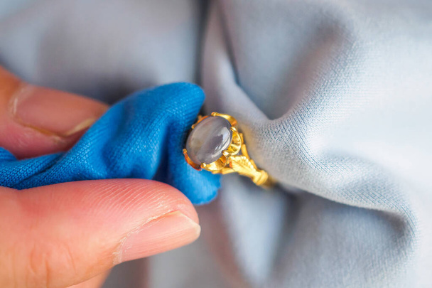 Sieraden hand polijsten en schoonmaken gouden sieraden ring met microvezel stof - Foto, afbeelding