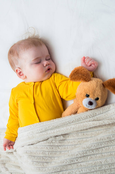Close-up portrait of a sleeping baby in an embrace with a toy . Vertical photo - Valokuva, kuva
