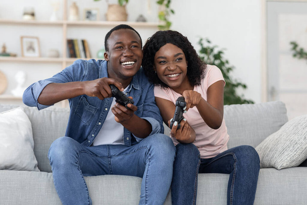 Joyful black man and woman with joysticks at home - Photo, Image