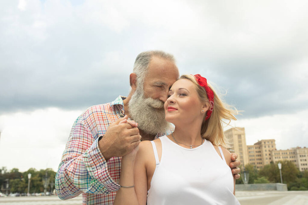 Beautiful couple outdoors. Mature bearded man and young woman. - Foto, afbeelding