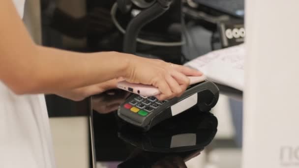 Mobile concetto di pagamento - Giovane donna paga per telefono contactless al sistema di carte di credito per i suoi nuovi vestiti - Filmati, video