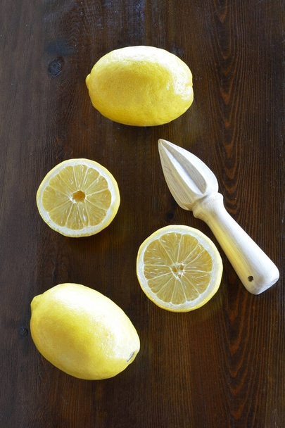 Limones sin cera y exprimidor de limón sobre mesa de madera - Foto, imagen