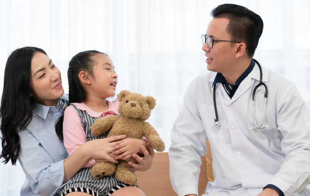 aasialainen lääkäri puhuu nuori tyttö ja äiti, jotka vierailevat lastenklinikalla sairaalassa. Terveysauto ja lääketieteellinen käsite - Valokuva, kuva