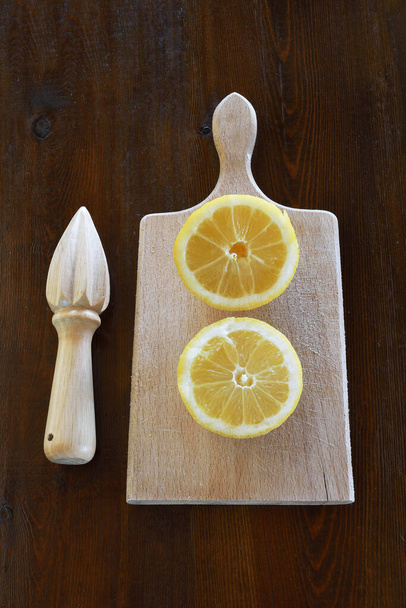 Helften citroen en citroenpers op houten tafel - Foto, afbeelding