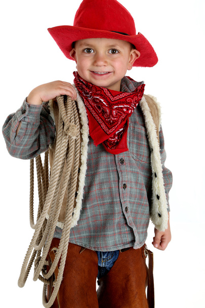 Cute very young cowboy holding a rope smiling - Fotó, kép