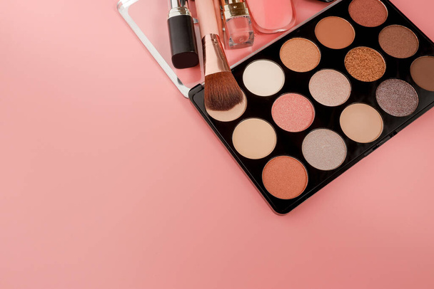 Various makeup productson pink background with copyspace. - Фото, изображение