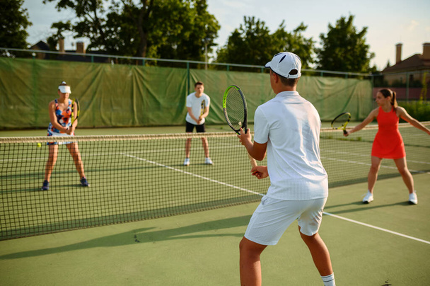 混合ダブルテニストレーニング、屋外コート。アクティブな健康的なライフスタイル,人々はラケットとボールでスポーツゲームをプレイ,ラケットとフィットネスワークアウト - 写真・画像