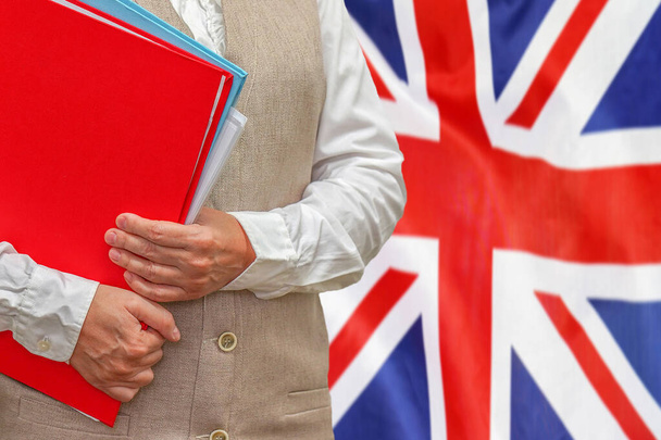 Woman holding red folder on United Kingdom flag background. Education and jurisprudence concept in UK - Photo, Image
