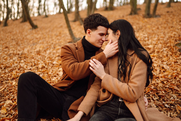 Lovely couple having fun together in the autumn forest. Fashion couple enjoying autumn weather. Fashion, lifestyle and autumn mood. - Фото, изображение