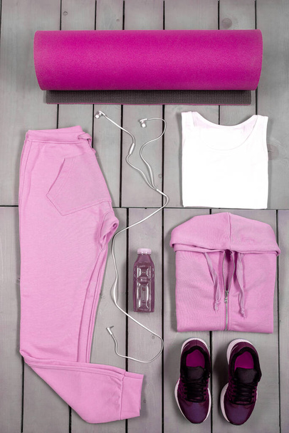 Overhead view womans workout outfit, Female sports equipment, pink sport on grey wooden background, Top view, flat lay - Fotoğraf, Görsel