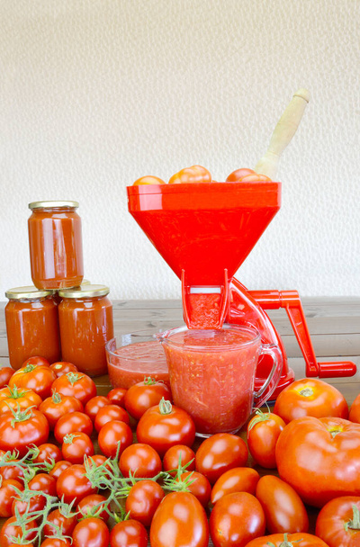 Coador de tomate, tomates frescos, molho de tomate fresco e enlatado e enlatamento em uma mesa de madeira - Foto, Imagem