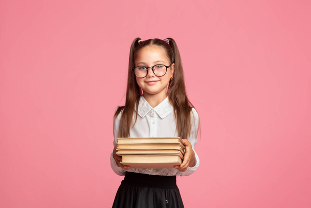 Концепція школи та бібліотеки. Маленька дівчинка в шкільній формі і окуляри тримає книги
 - Фото, зображення