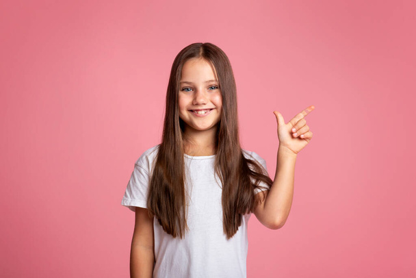 Kid with long hair presenting product. Happy little girl shows to empty space - Foto, imagen