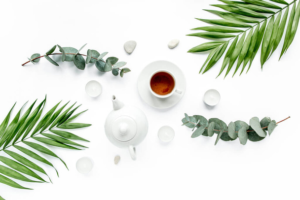 teapot, tea mug and palm leaf branches, flat lay, top view - Foto, Imagen