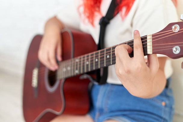 Hands of a teenage girl playing an acoustic guitar - Foto, imagen