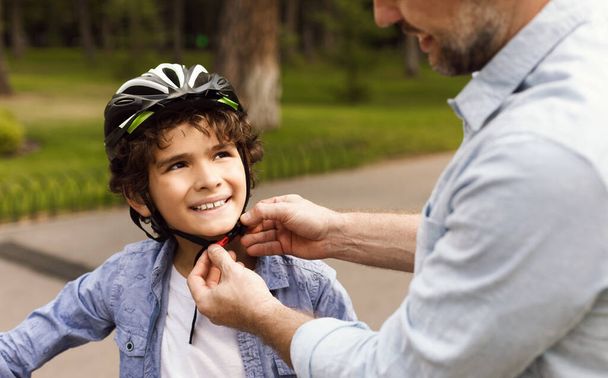 Adult man putting safety helmet on his son - Photo, Image