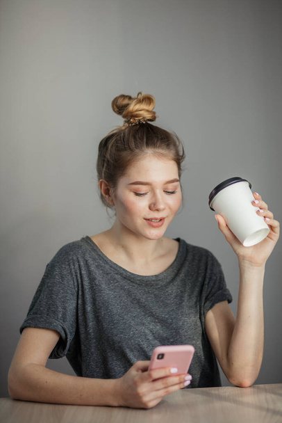 young woman sitting at a table with a coffee using mobile phone. - Photo, Image