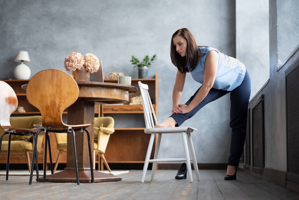Trabajadora de oficina de pie en postura de yoga estiramiento pierna usando silla. - Foto, Imagen