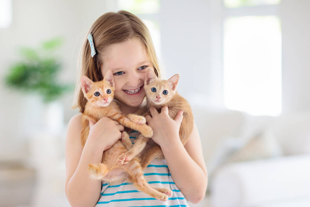Bebek kedi kucağında. Çocuklar ve evcil hayvanlar. Küçük kız evde küçük şirin kediciğe sarılıyor. Çocuklu bir aile hayvanı. Evcil hayvanlı çocuklar. - Fotoğraf, Görsel
