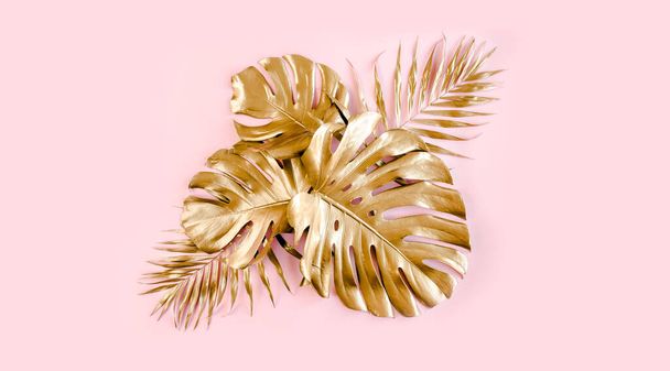 Gold tropical palm leaves Monstera on pink background. Flat lay, top view minimal concept. - Фото, изображение