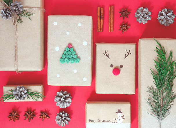 Weihnachtliche Komposition von Geschenkschachteln aus Bastelpapier auf rotem Hintergrund. Das Konzept der Null-Verschwendung. Umweltfreundliches natürliches Dekor für die Verpackung von Weihnachtsgeschenken. Flache Lage.Knolling - Foto, Bild