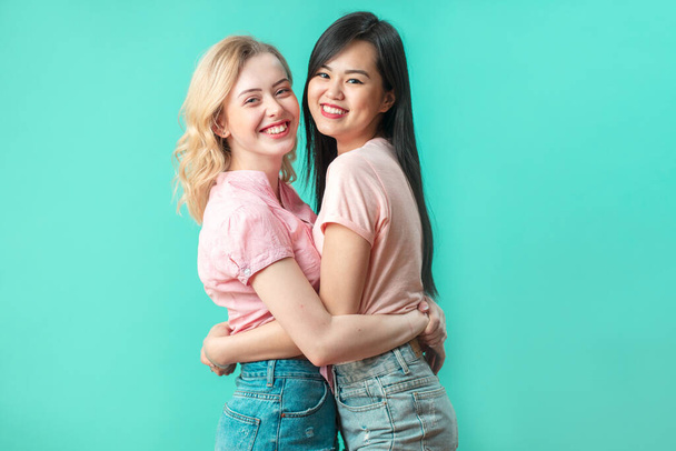 Multiethnic young women hugging at blue studio background with copy space - Fotoğraf, Görsel