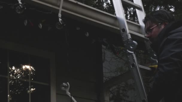 mies käyttää tikkaita pystyttää jouluvalot - Materiaali, video