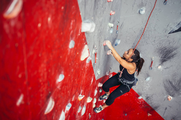 Young fitness woman doing professional bouldering in climbing gym indoors - Foto, Bild