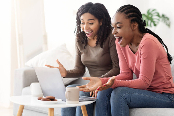 Emotional african american female friends looking at laptop screen - Photo, Image