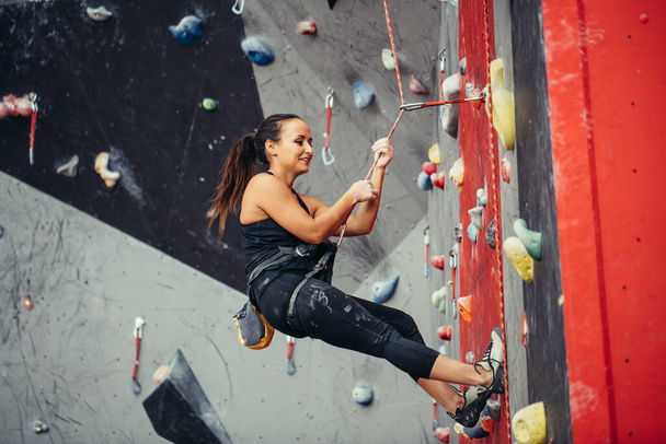 Активна щаслива жінка висить на щільній мотузці в тренувальному центрі скелелазіння
 - Фото, зображення