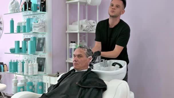 lava el cabello de un hombre en un salón de belleza - Imágenes, Vídeo