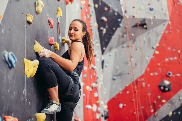Young climber woman climbing on practical rock in climbing center, bouldering - Foto, Imagem