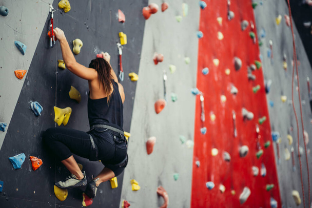 Sporty young woman training in a colorful climbing gym. - Fotoğraf, Görsel
