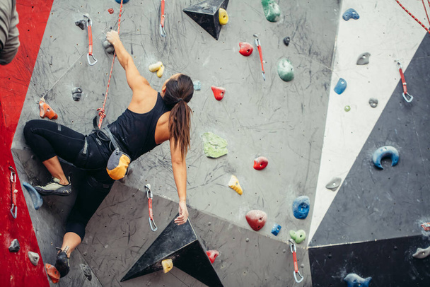 Fit sporty student girl moving up at rock climbing wall at the gym - Fotoğraf, Görsel