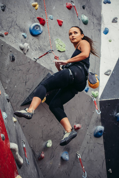 Sporty young woman training in a colorful climbing gym. Free climber girl climbing up indoor - Zdjęcie, obraz
