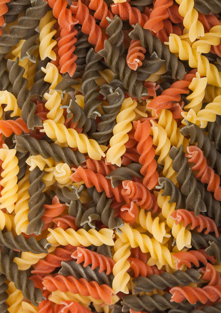 Raw homemade tricolore fusilli pasta as texture background. Top view - Foto, afbeelding