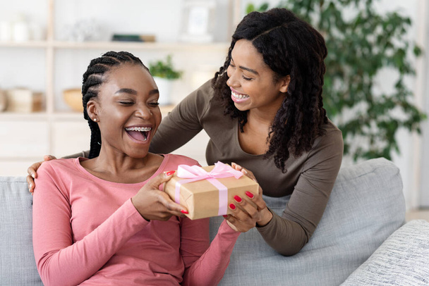 Mujer negra dando regalo a su novia en casa - Foto, imagen