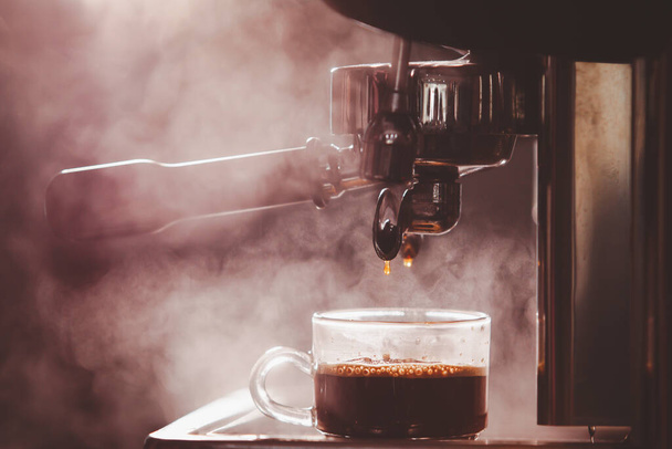 Barista brewing the espresso coffee by using high pressured espresso machine in a small coffee shop. Coffee machinery in coffee shop. - Foto, afbeelding