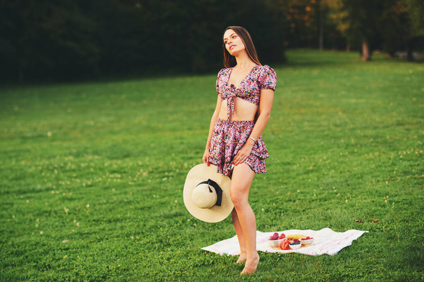 Porträt einer schönen jungen Frau im Freien, die einen schönen Tag im grünen Park, gesunde Ernährung und die Zeit des Obstsnacks genießt - Foto, Bild