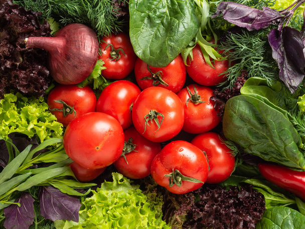 トップビュー-様々な食用新鮮なハーブ、緑と紫の緑が円の中に配置され、中央には赤いトマト、ピーマン、バーガンディ玉ねぎがあります。 - 写真・画像